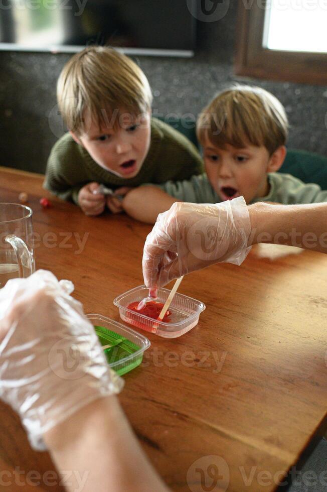 DIY science lab at home dad and kids explore safe chemical reactions. Bright colors and wide eyed excitement. photo