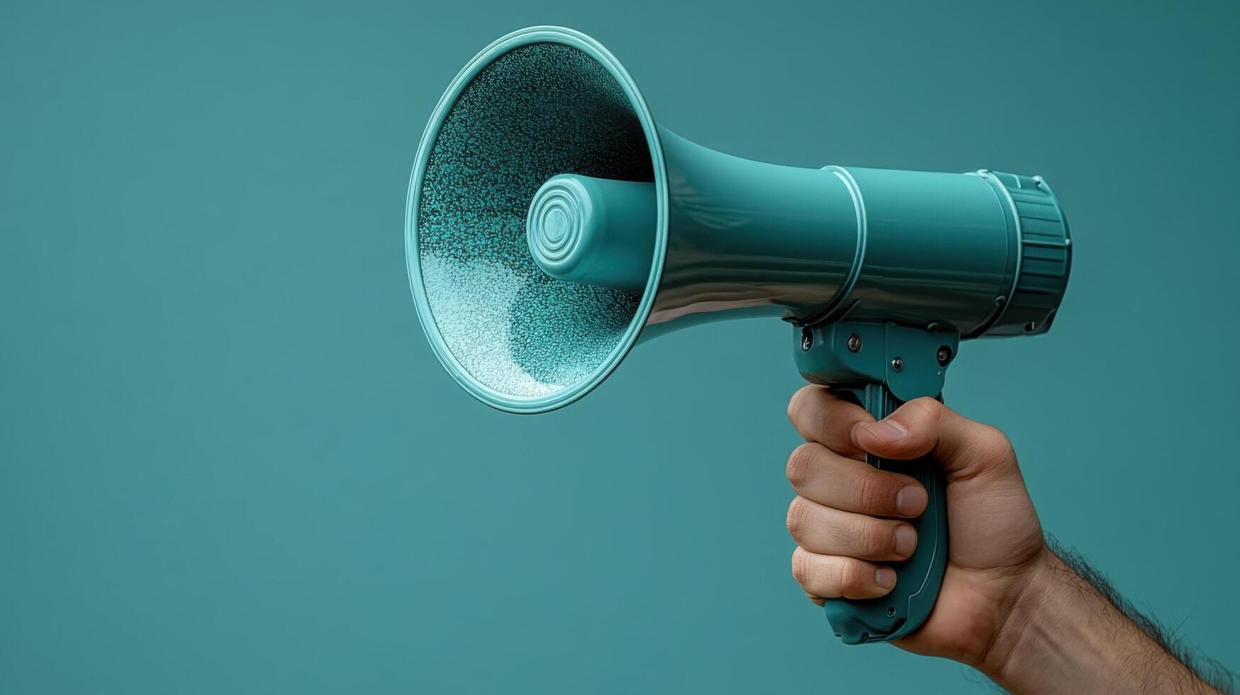 Hand holding a teal megaphone against a solid colored background in a bright and engaging setting photo