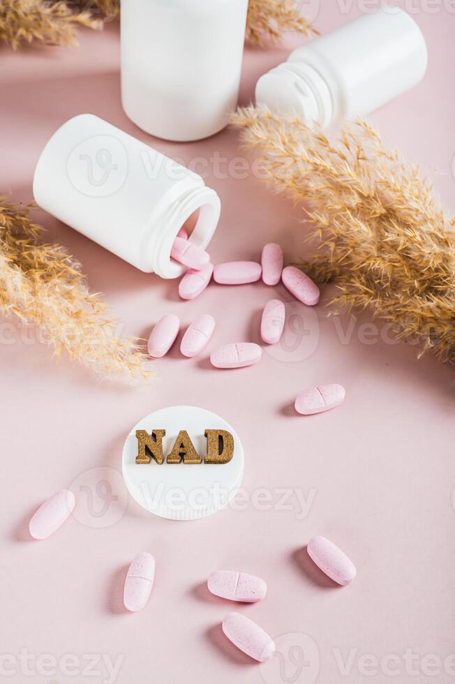 NAD molecule in pills for anti-aging and biohacking on pink background vertical view photo