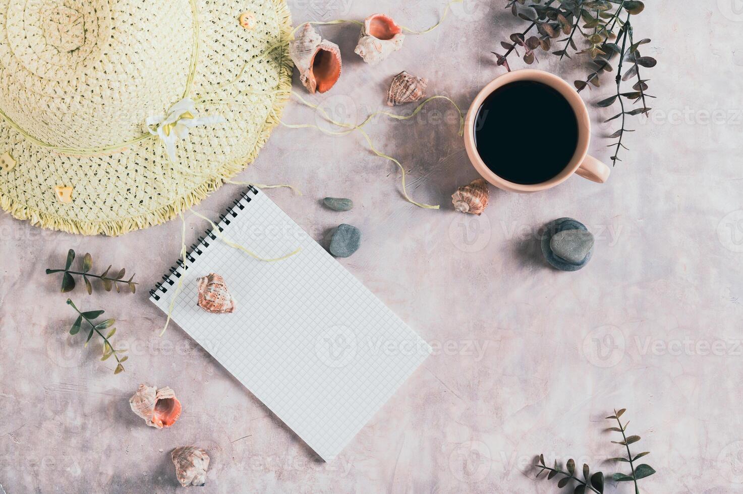 Travel planning notebook, hat, seashells and cup of coffee on table top view photo