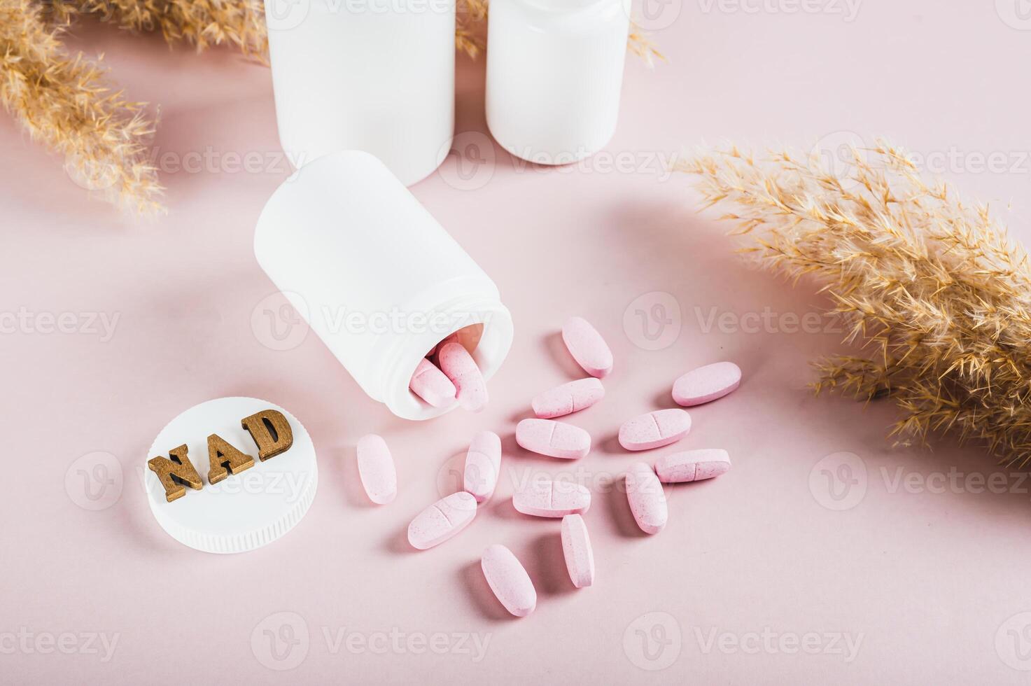 NAD molecule in pills for anti-aging and biohacking on pink background photo