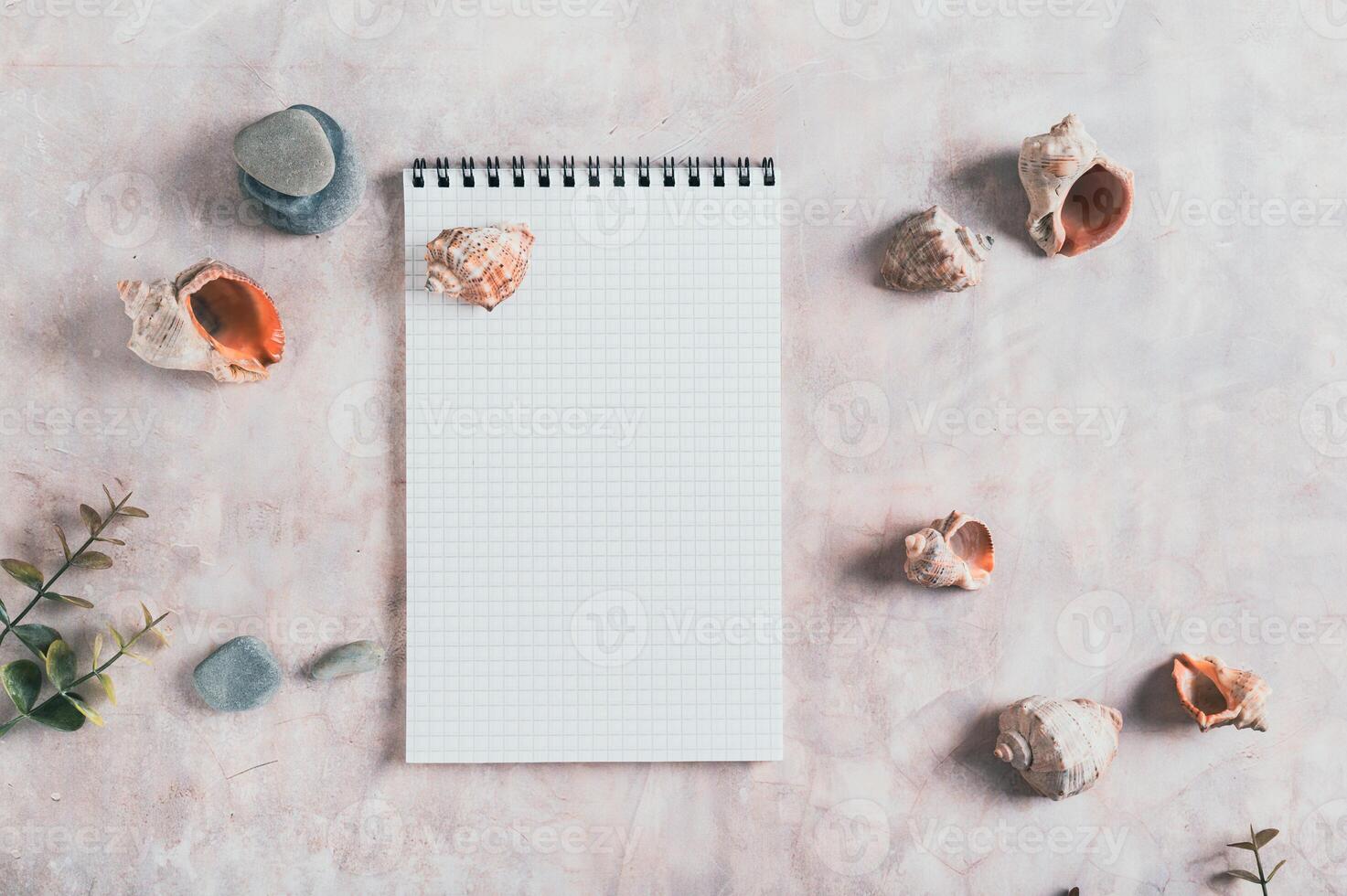 Travel planning notebook, shells and stones on table top view photo