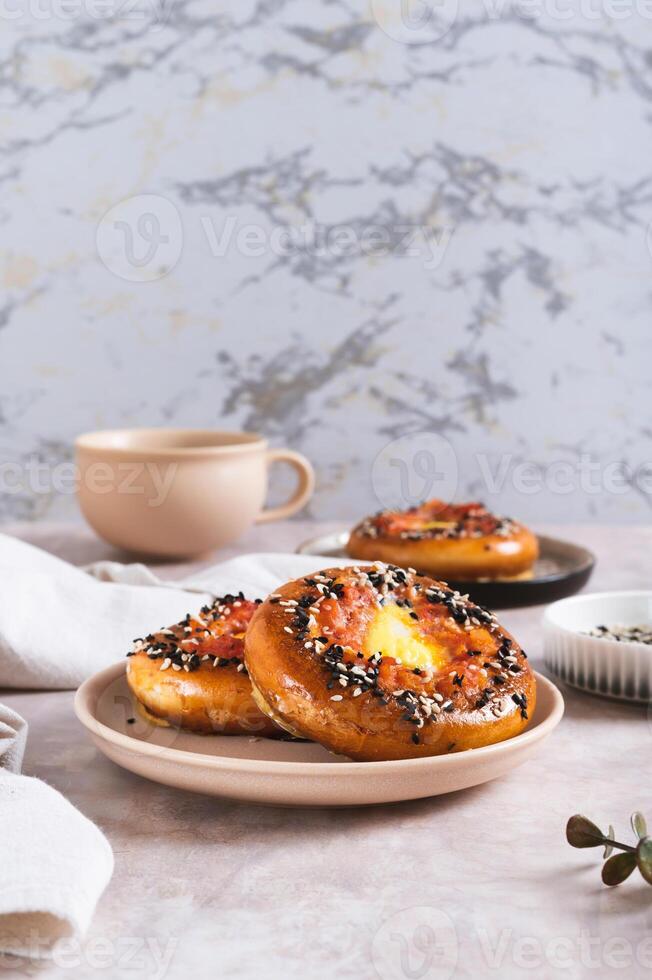 Baked bagels with tomato and quail egg on a plate on the table vertical view photo