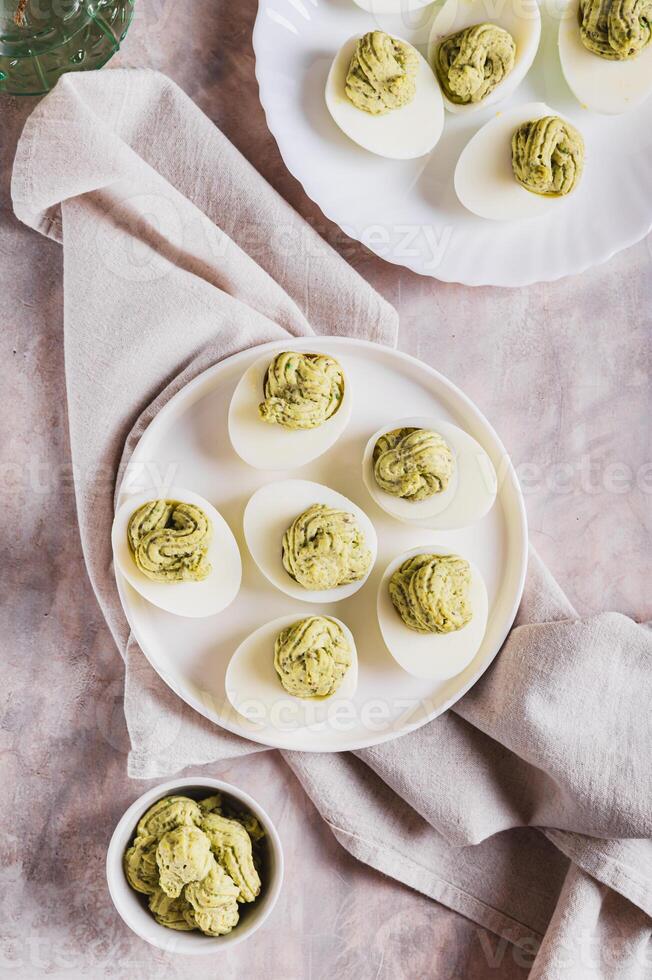 Avocado deviled eggs for appetizer on plate on table top and vertical view photo