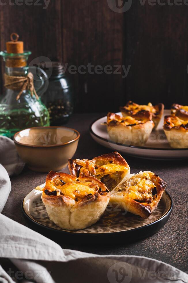 Mini tartlets with caramelized onions and cheese on a plate on a table vertical view photo