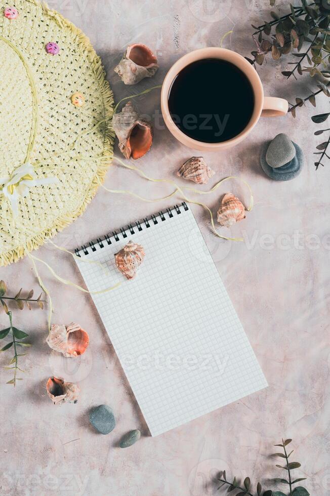 Notebook, beach hat, shells and stones on the table top and vertical view photo
