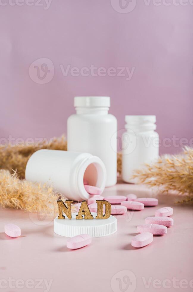 Nicotinamide adenine dinucleotide anti-aging pills and bottles on the table vertical view photo