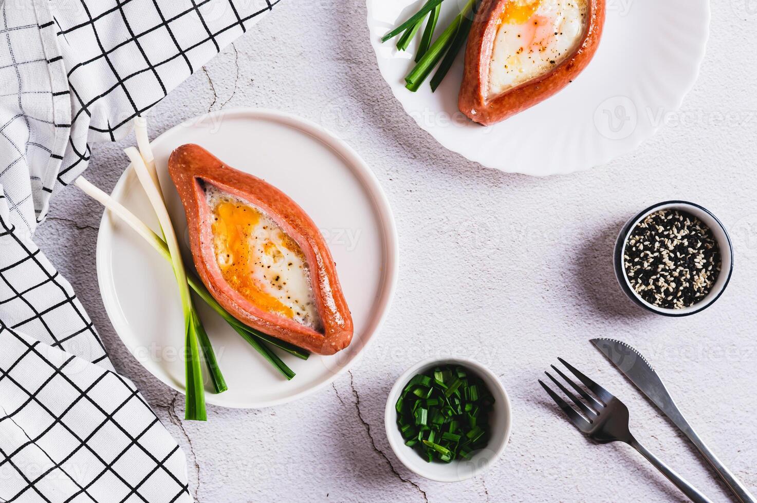 Fried egg in a sausage in the form of khachapuri on a plate on the table top view photo