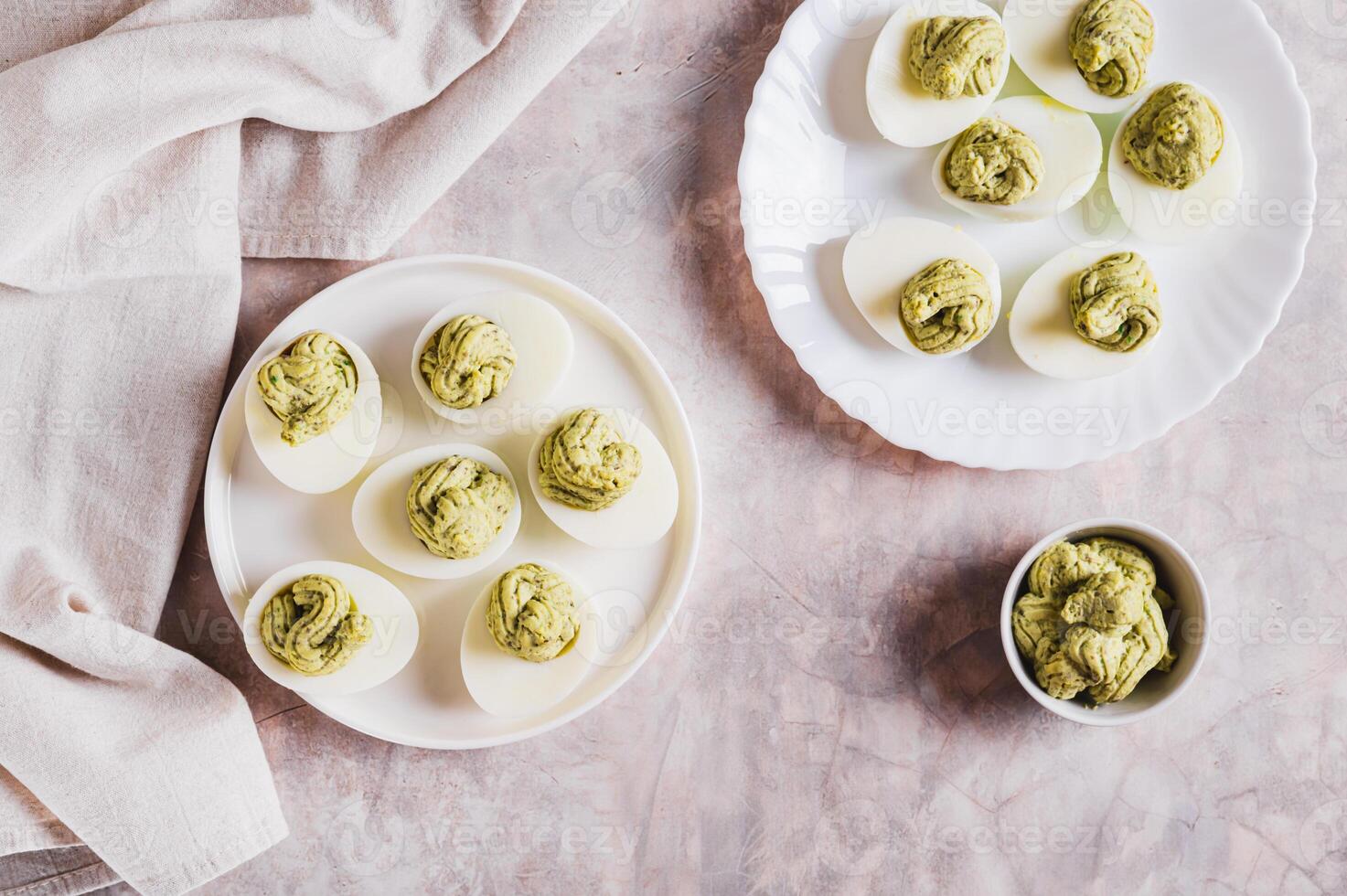 Eggs stuffed with avocado and yolk mixture on a plate on a table top view photo