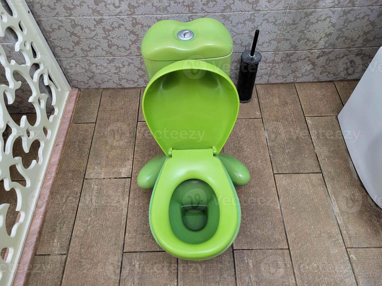 A green children's toilet on a background of beige tiles, stands in the bathroom photo