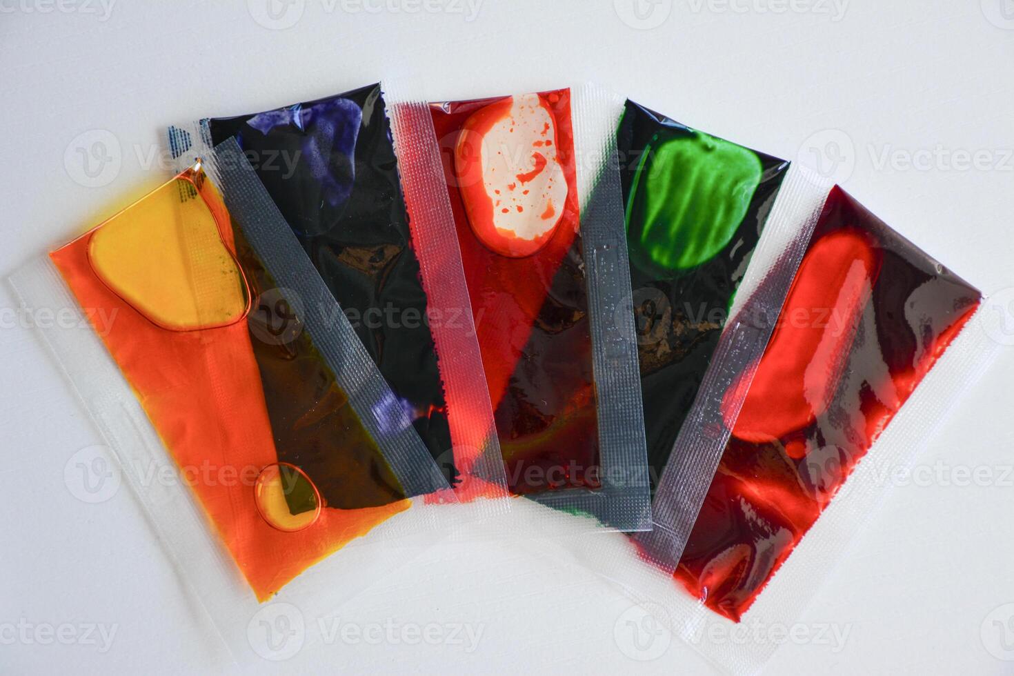 liquid food colors in transparent pouches. Vibrant hues orange, red, green, purple, blue on white background. Rich eadible dyes for eggs, pastry photo