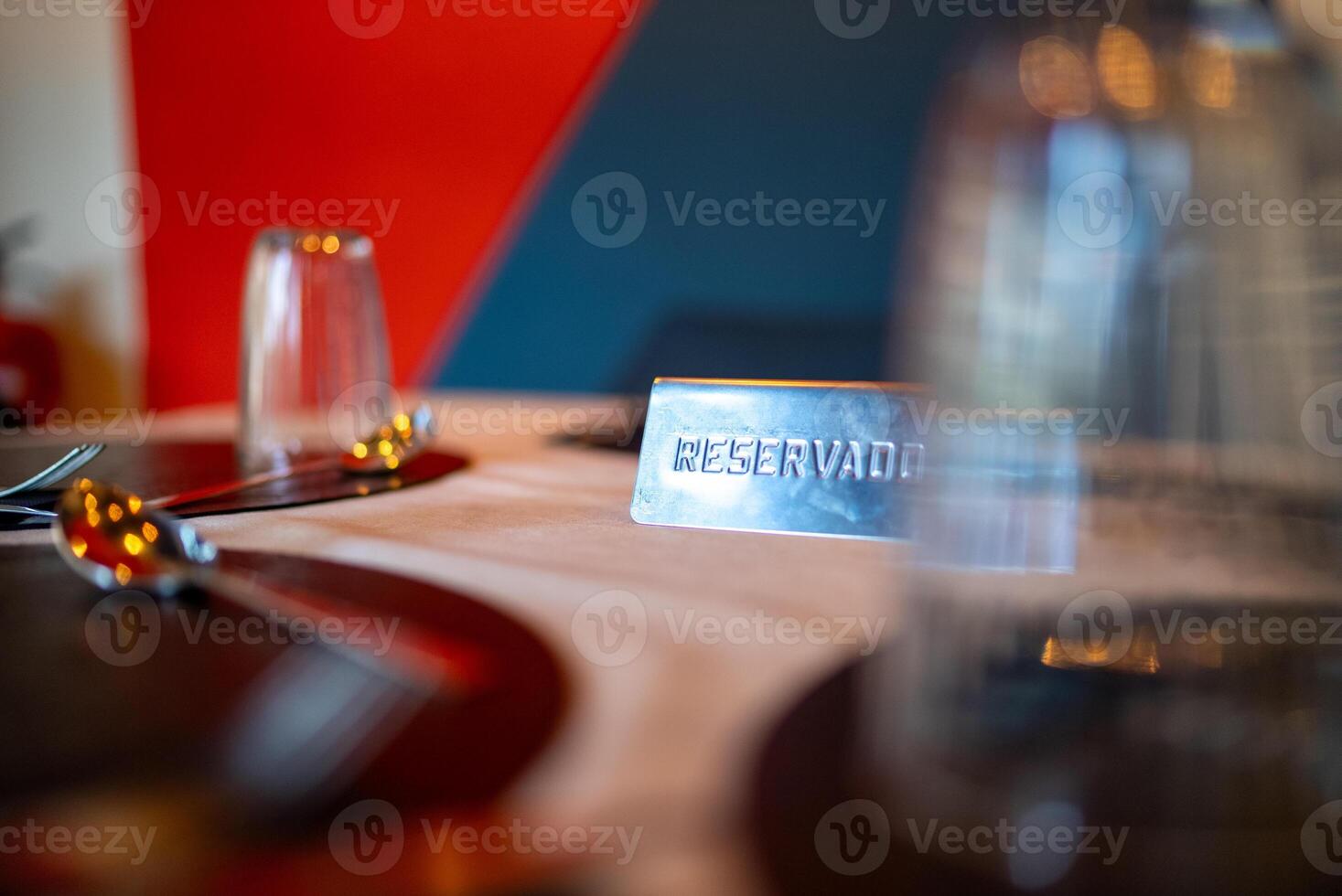 Metal reservado sign resting on an elegantly set restaurant table, marking a reserved dining area, complemented by neatly arranged cutlery and glasses for anticipated guests photo