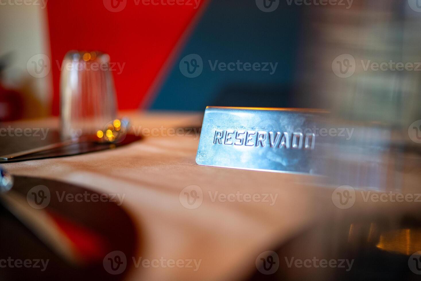 Metal reservado sign placed on a set restaurant table, indicating a reservation, with glasses, plates, and cutlery arranged, creating an elegant and inviting ambiance photo