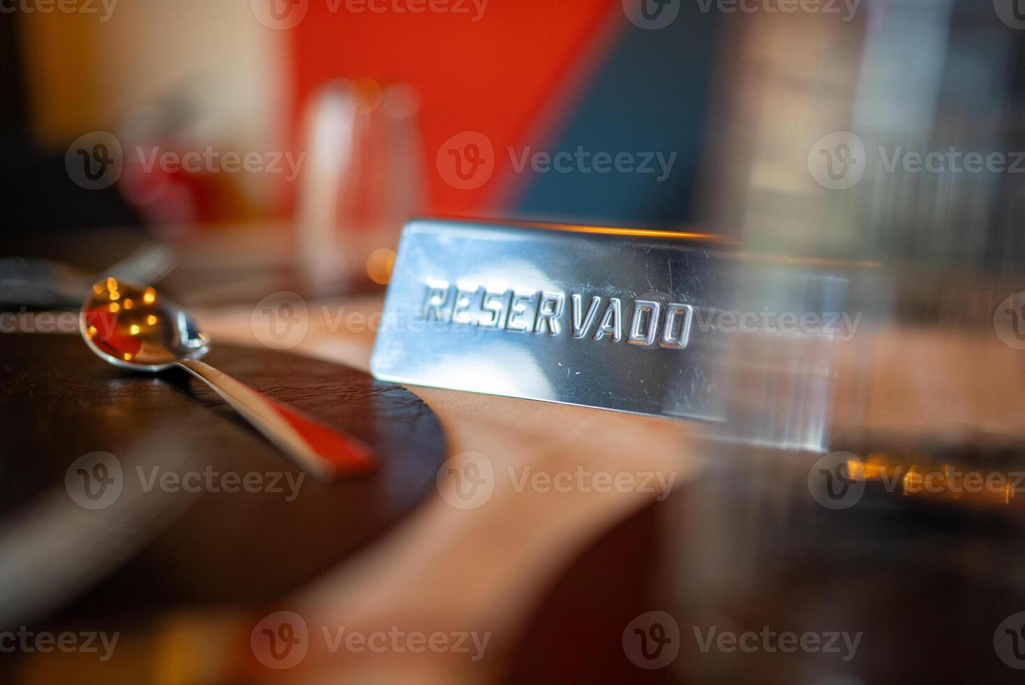 Reserved sign resting on a restaurant table beside a spoon, clearly indicating a booked table. Perfect for special occasions, business meetings, or romantic dinners photo