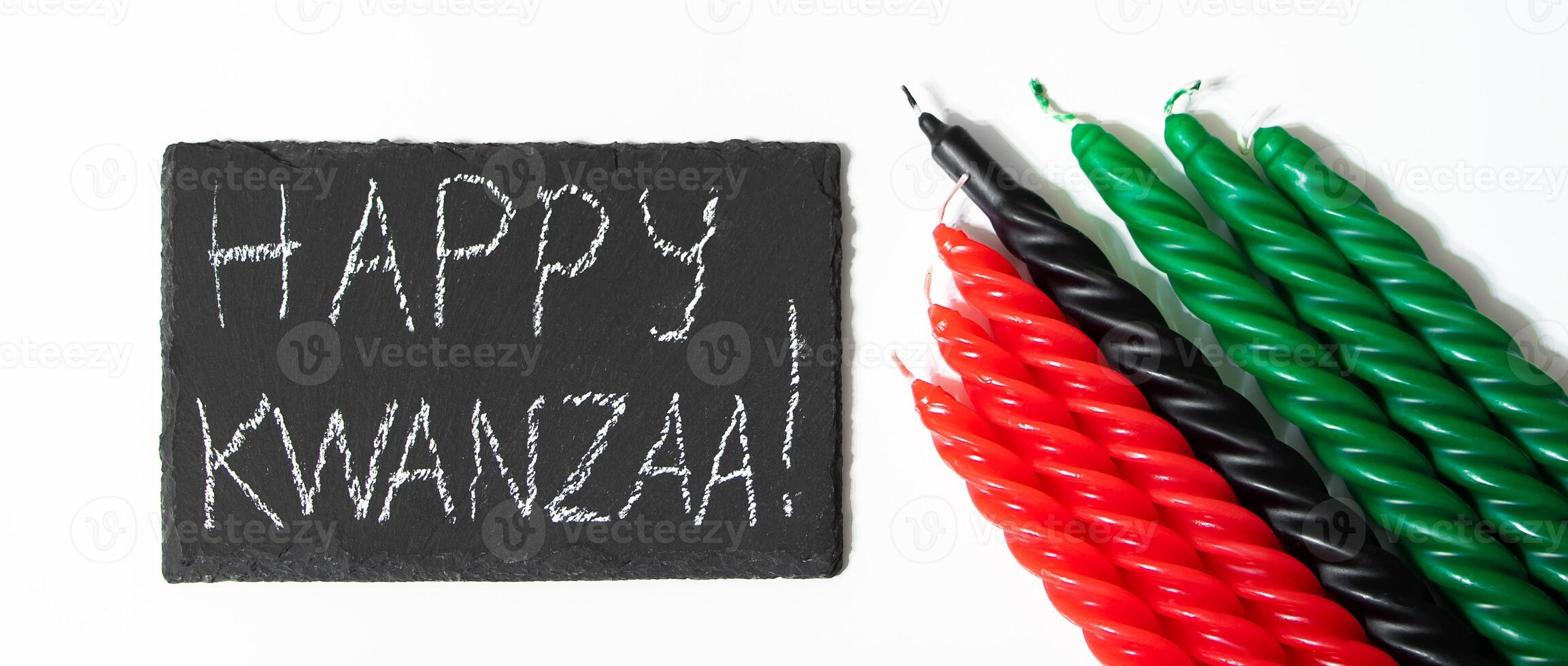 Happy Kwanzaa concept. Afro-American holiday. Congratulatory lettering and seven candles - red, black and green. African heritage symbol on white background photo