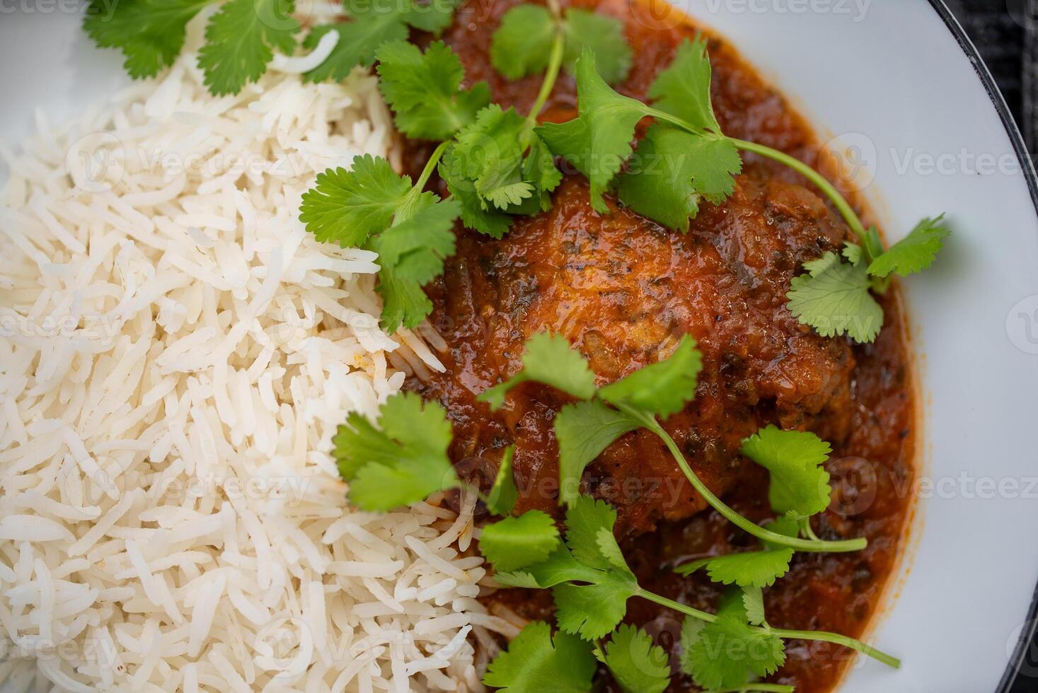 Delicious chicken curry served with fluffy basmati rice and garnished with fresh coriander leaves, creating a vibrant and aromatic culinary experience photo