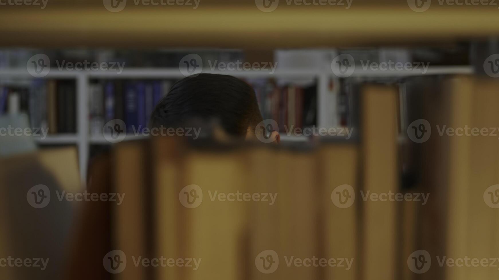 A Person Positioned Behind a Bookshelf Inside a Calm and Inviting Library Environment. Media photo