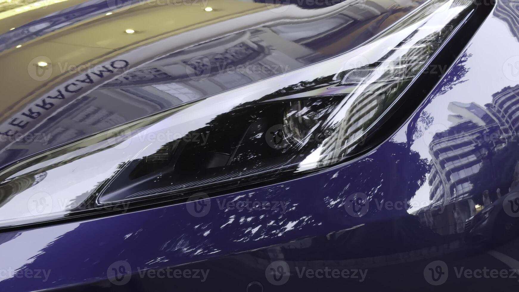 Close up on blue sports car headlight reflecting city buildings. Action photo