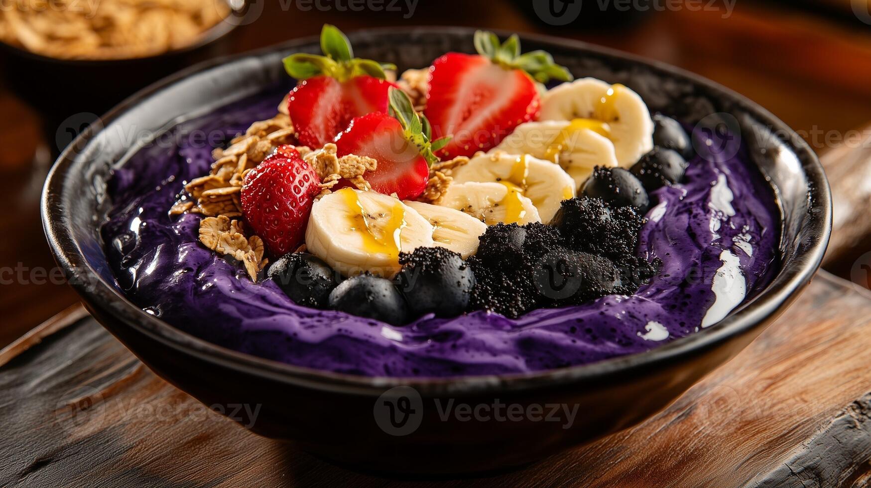 Acai Bowl with Strawberries, Banana Slices, Blueberries and Granola in a Dark Bowl photo