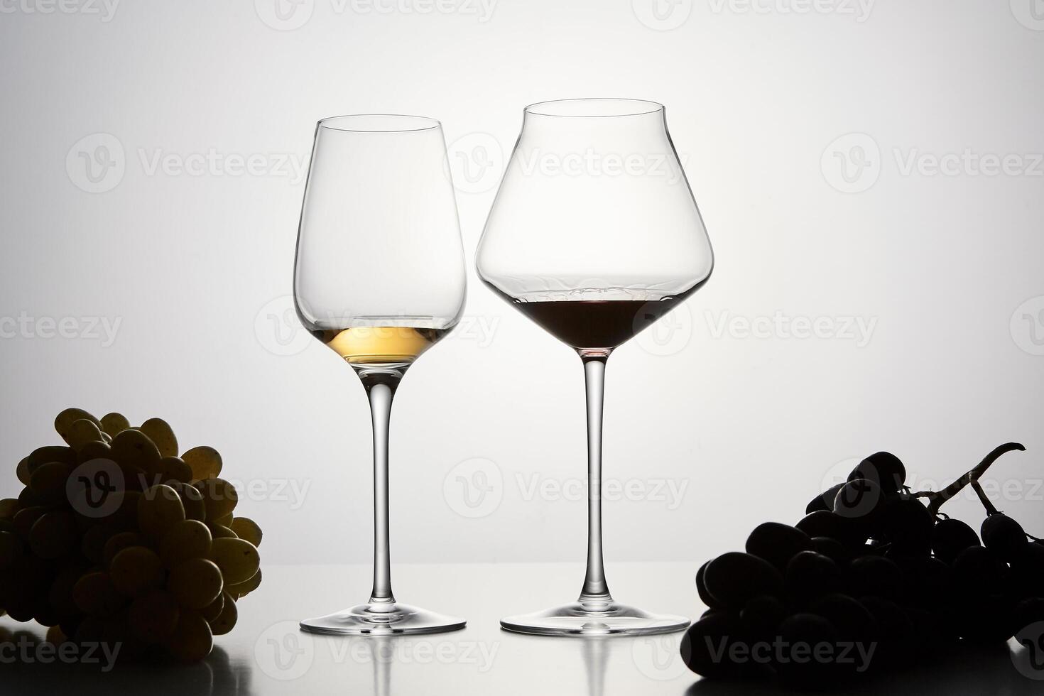 Red, white wine in stemware with dark grapes. photo