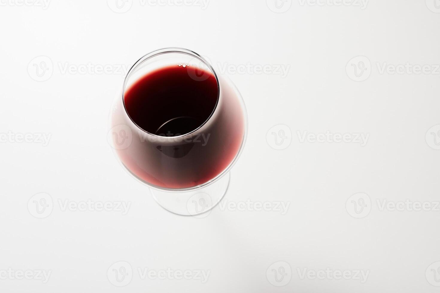 Top view of red drink poured into wine glass on white. photo