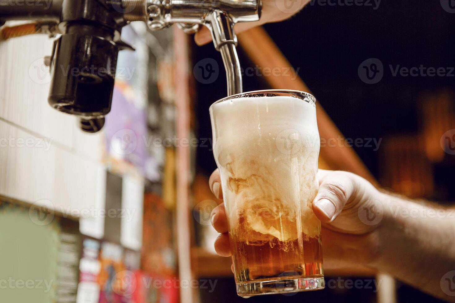 Man Pouring Glass of Golden Beer With Rich Foam at Lively Bar photo