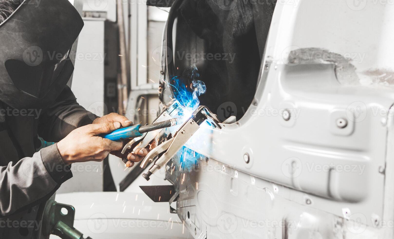 Worker in protective mask welds car metal elements of bodywork. Working with carbon dioxide welding. photo