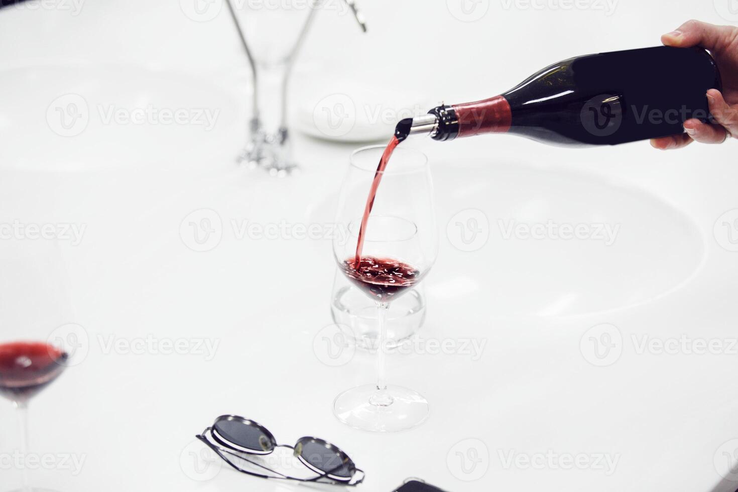 Close-up of sommelier pouring red wine into wine glass. Training and wine tasting. photo