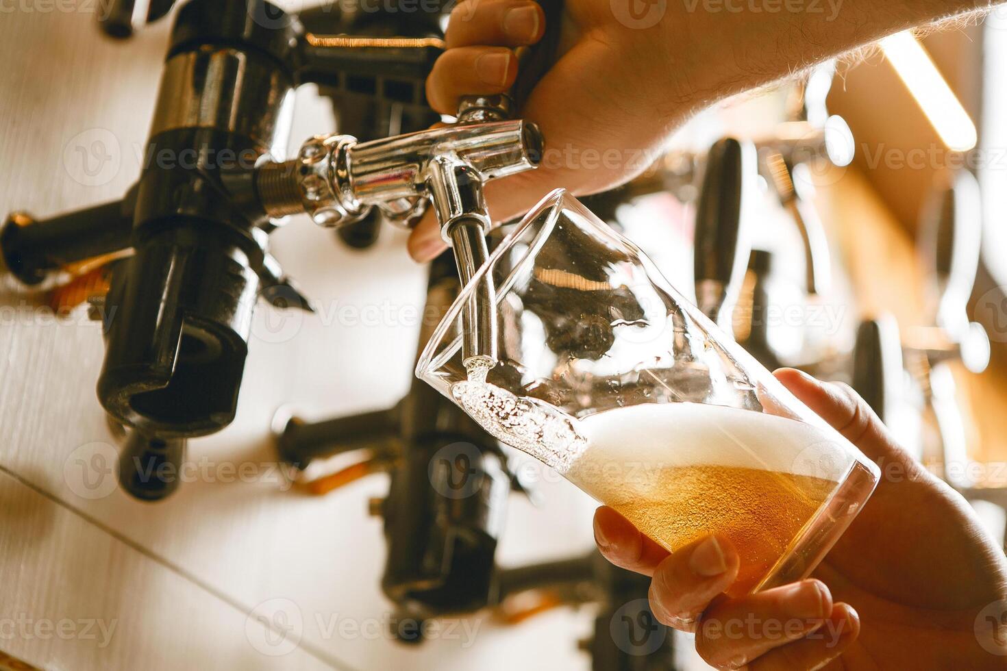 Pouring Golden Beer Into Glass From Tap in Well-Lit Bar at Afternoon Gathering photo