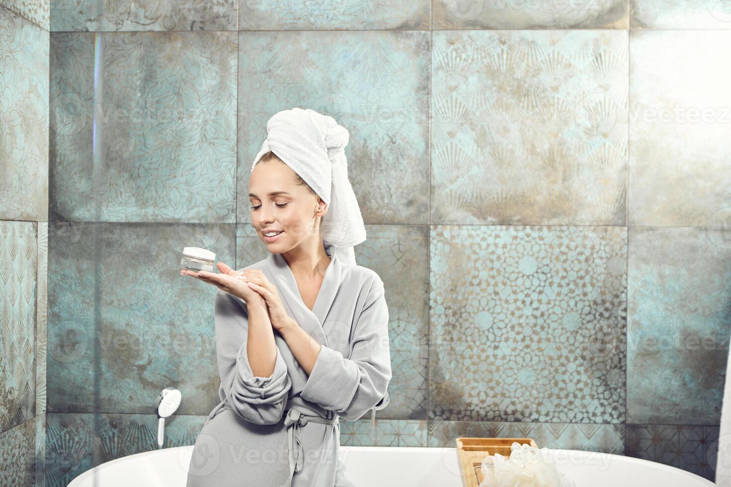 Girl in the bathroom is going to apply a rejuvenating cream on face. photo
