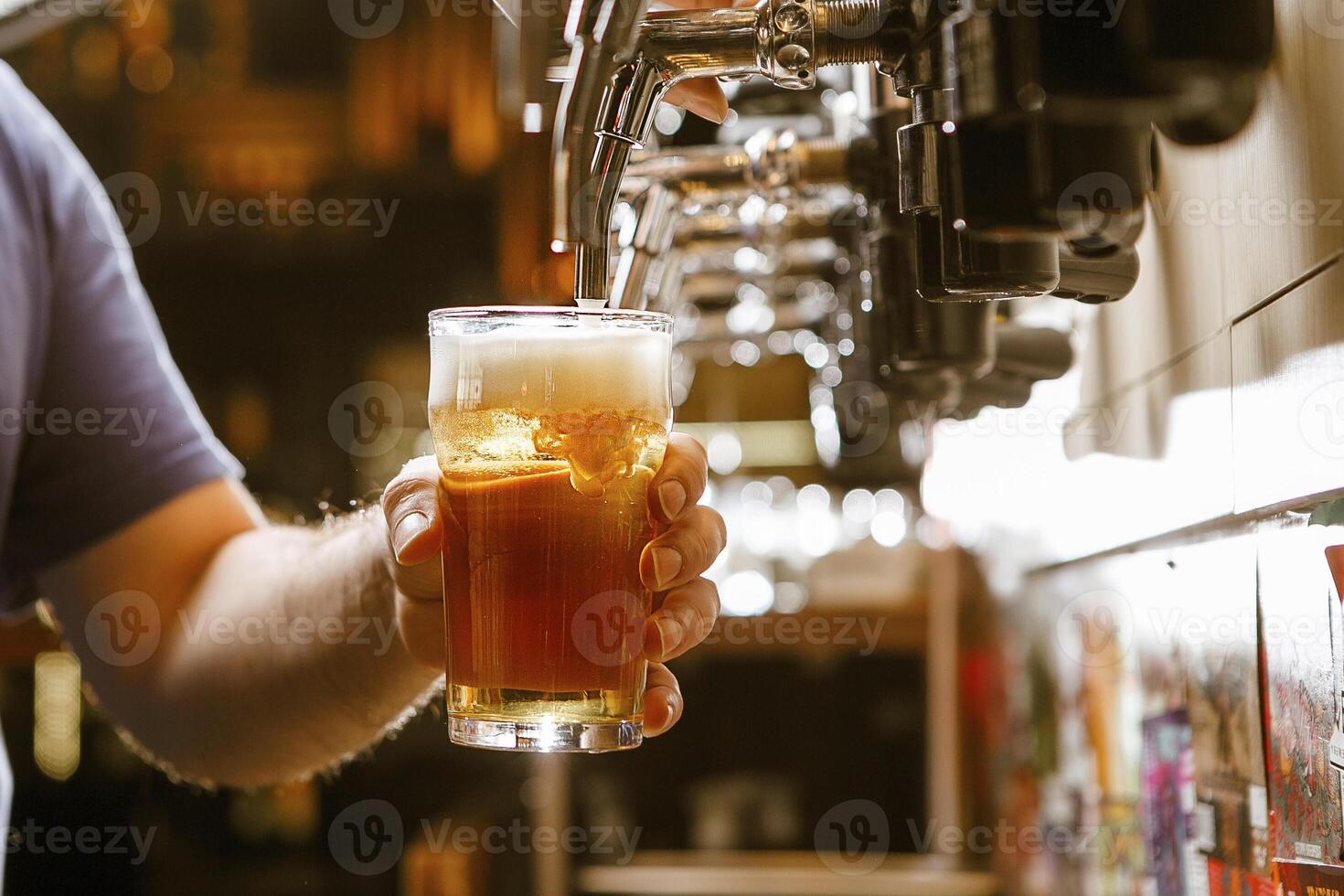 Bartender Pouring Cold Beer Into Glass Under Tap at Busy Pub photo