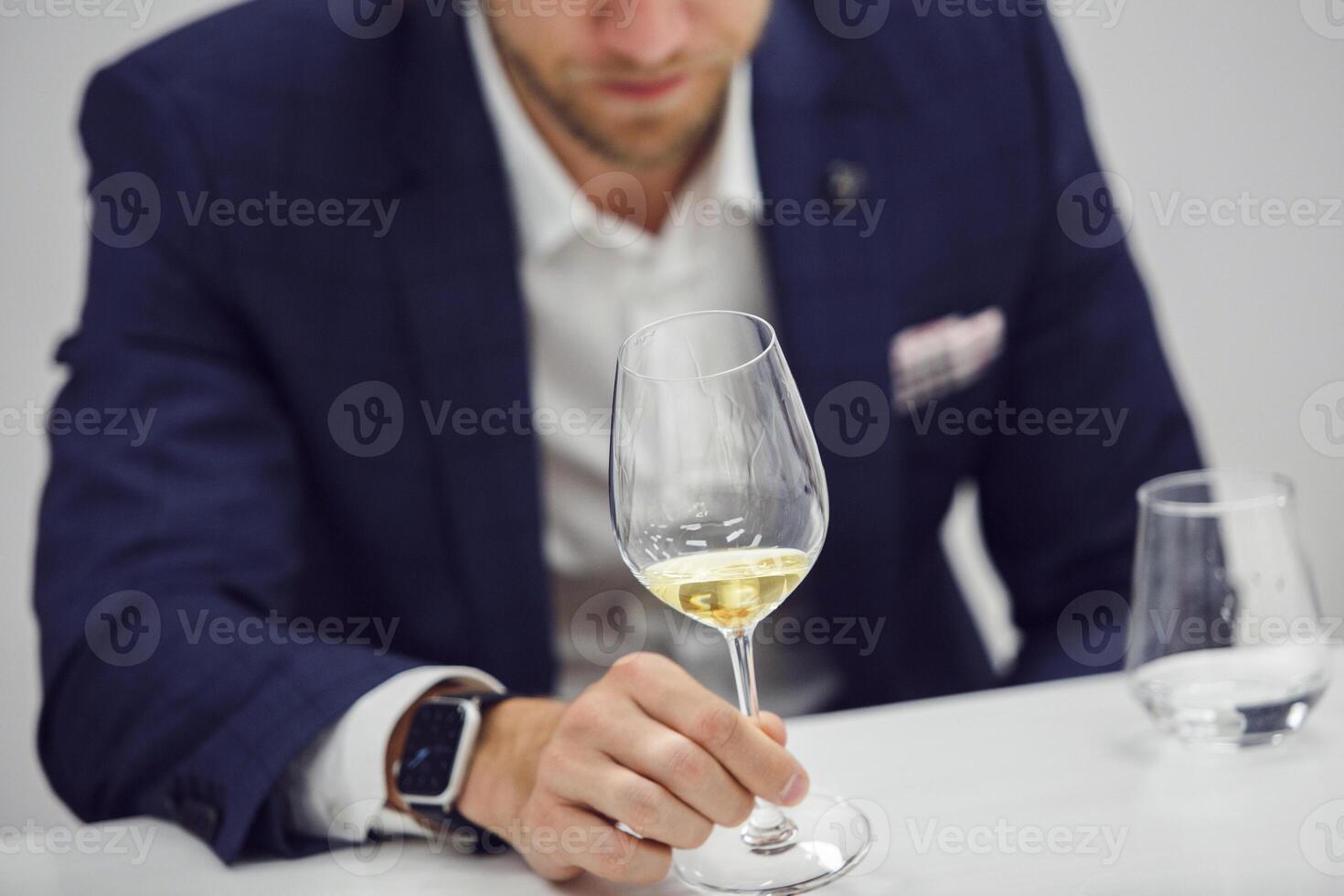 European wine enthusiast evaluating white wine at wine tasting based color rating, close up faceless shot. photo