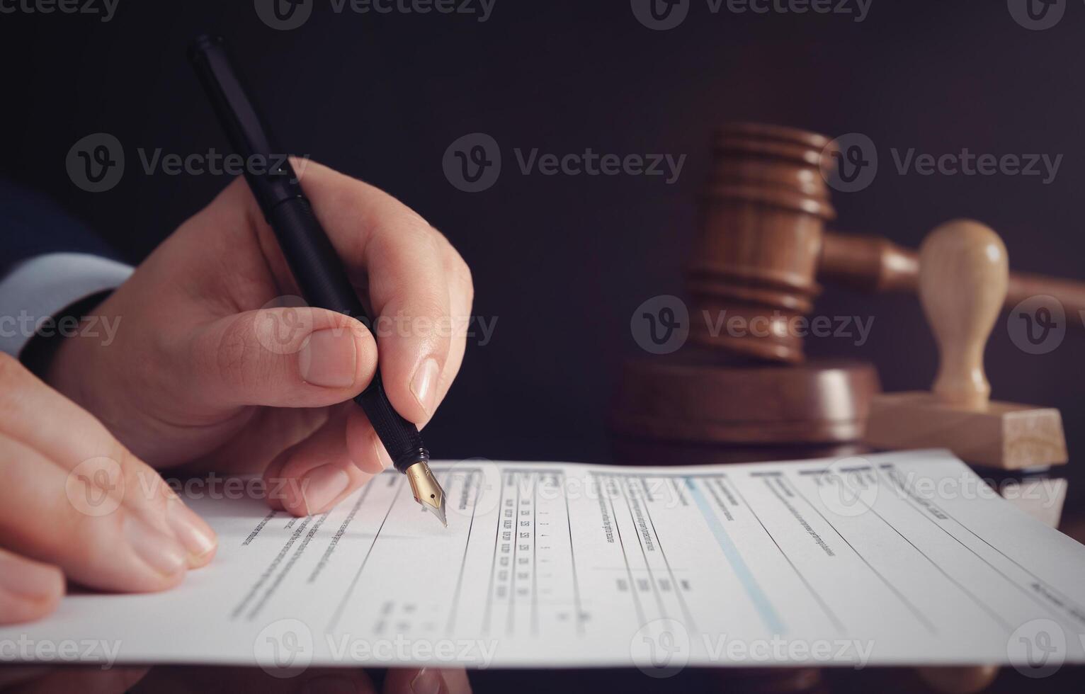 A man signing a contract with a pen and a gavel photo
