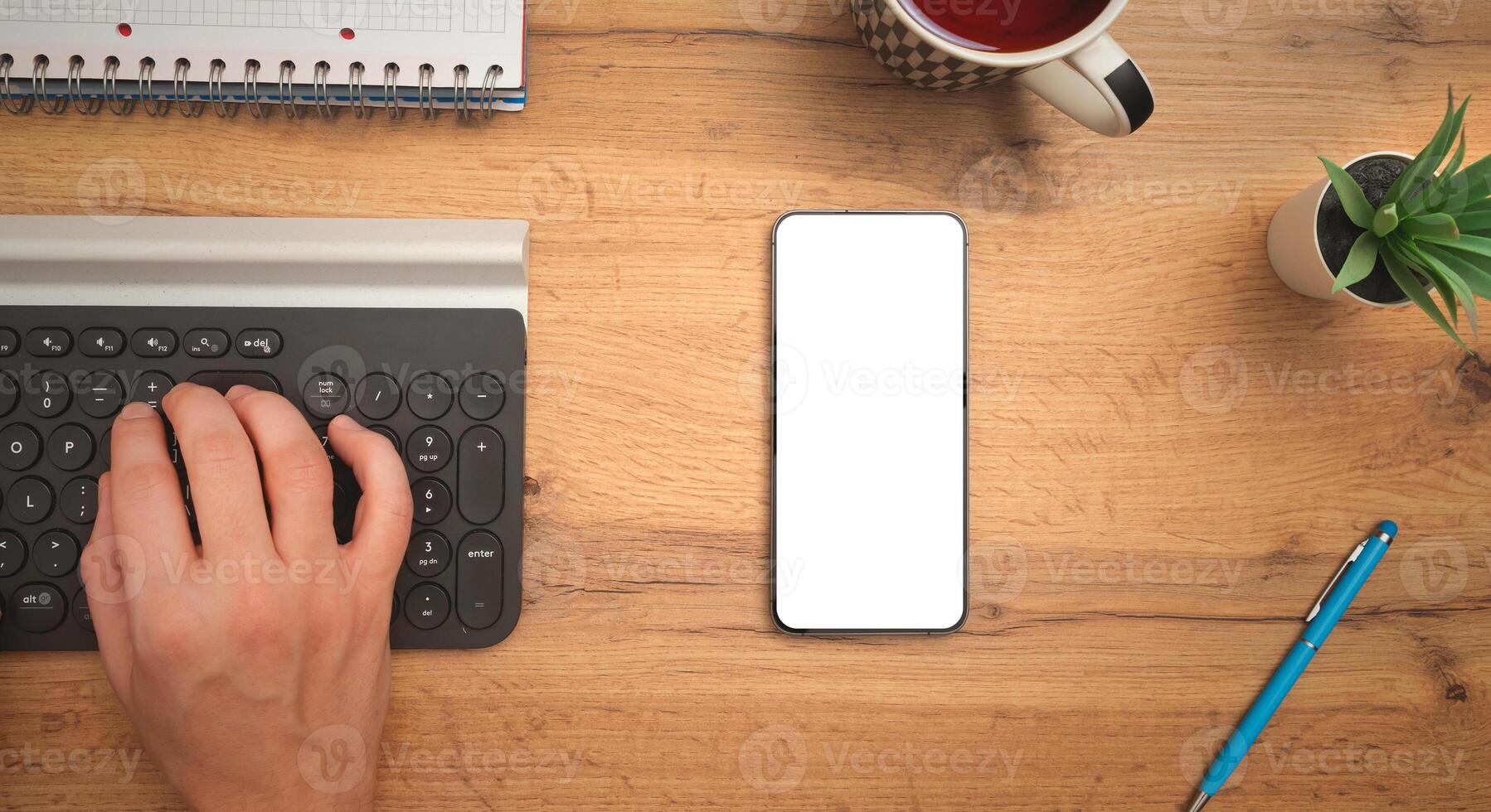 A person's hands on a keyboard and a phone photo
