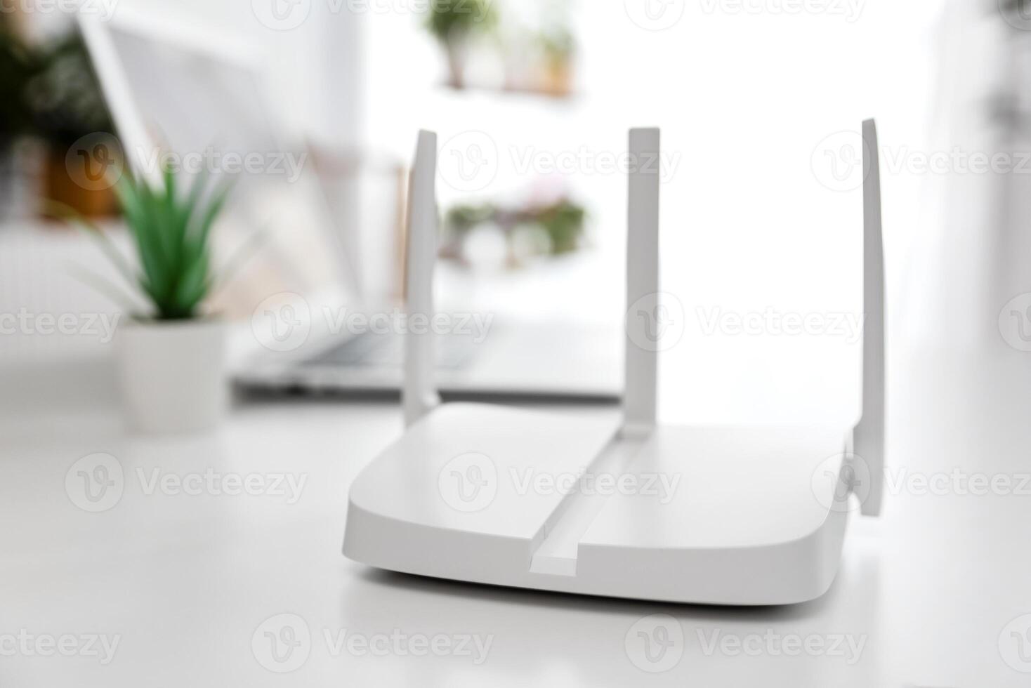 A white router sitting on a table in front of a laptop photo