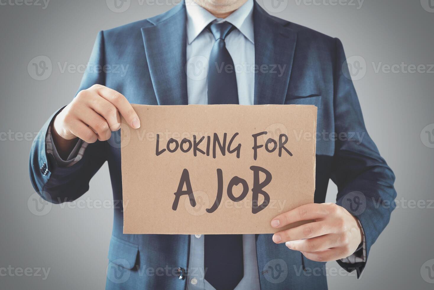 A man in a suit holding a sign that says looking for a job photo