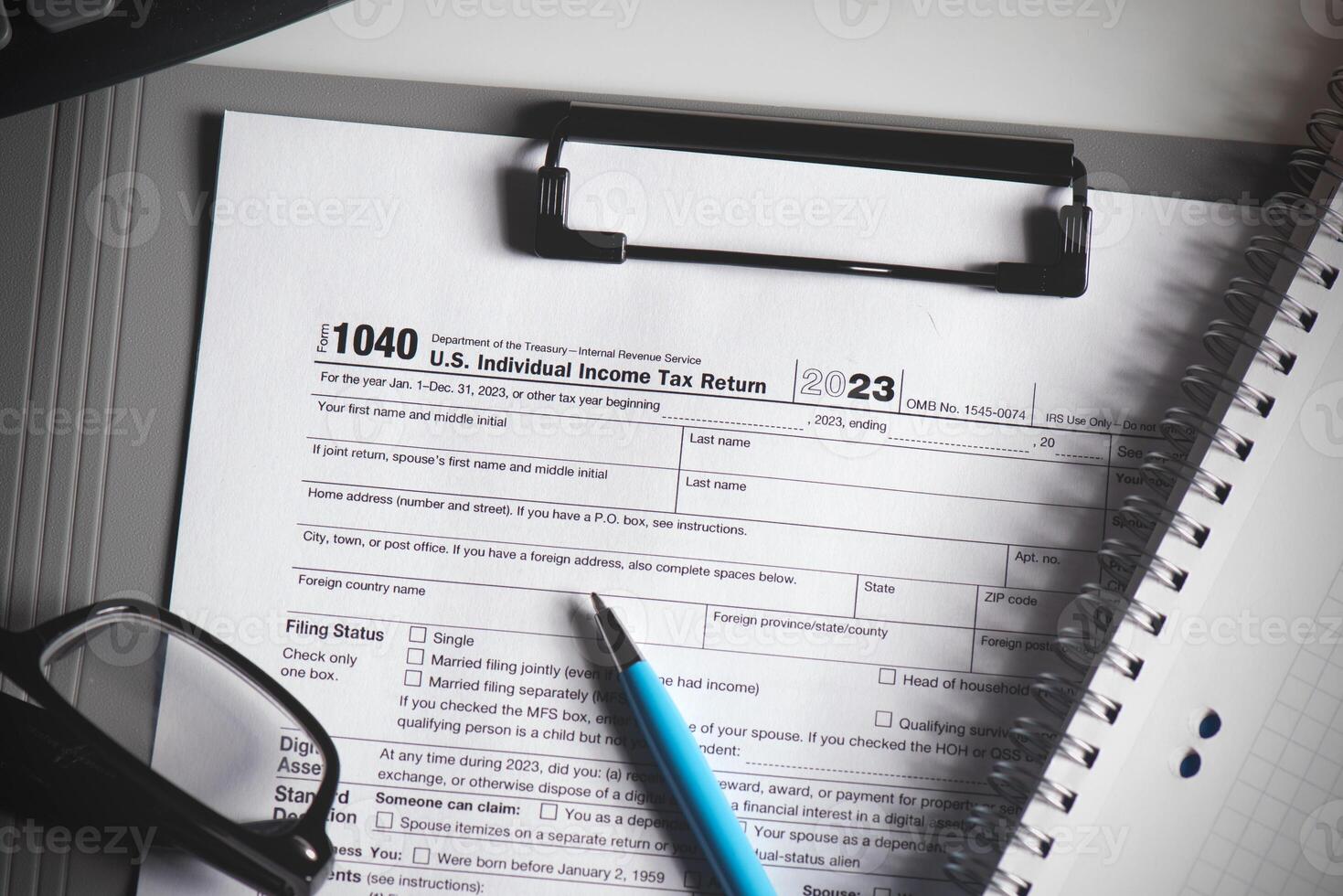 A tax form is on a clipboard with a pen next to it photo