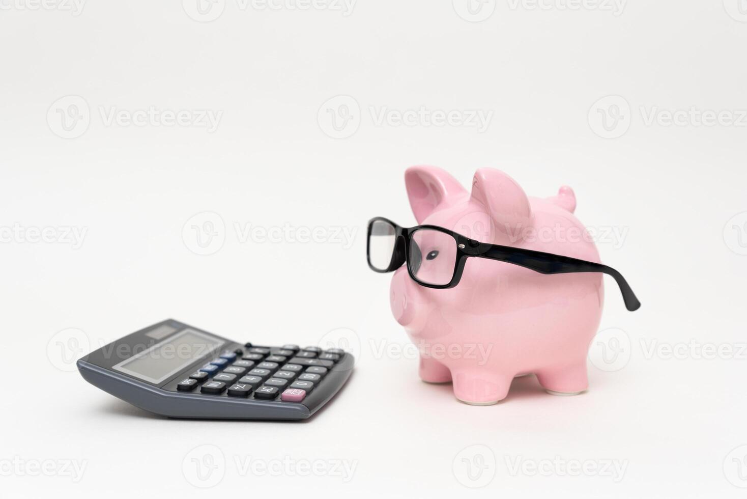 Pink piggy bank with glasses and calculator on white background photo