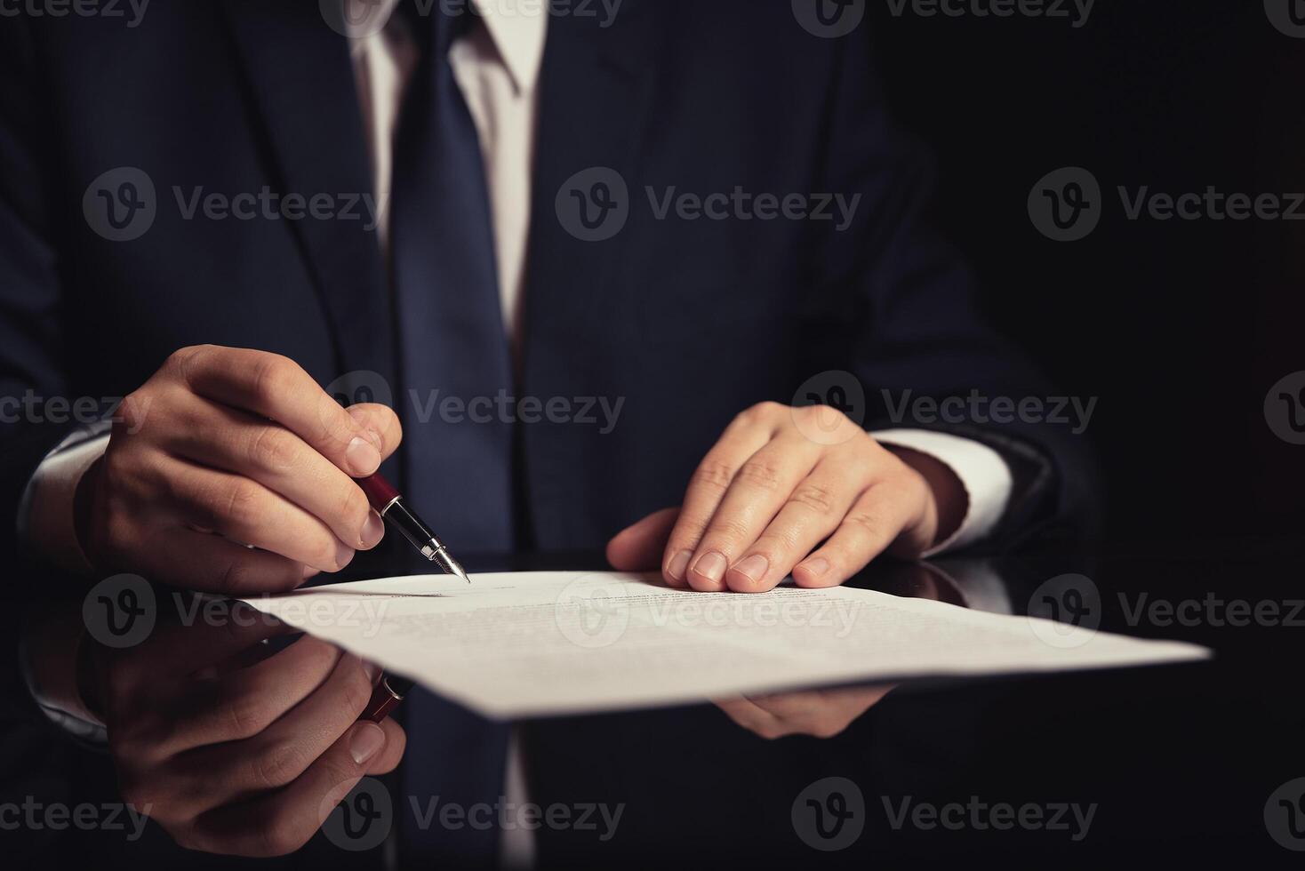 A man in a suit is signing a document photo