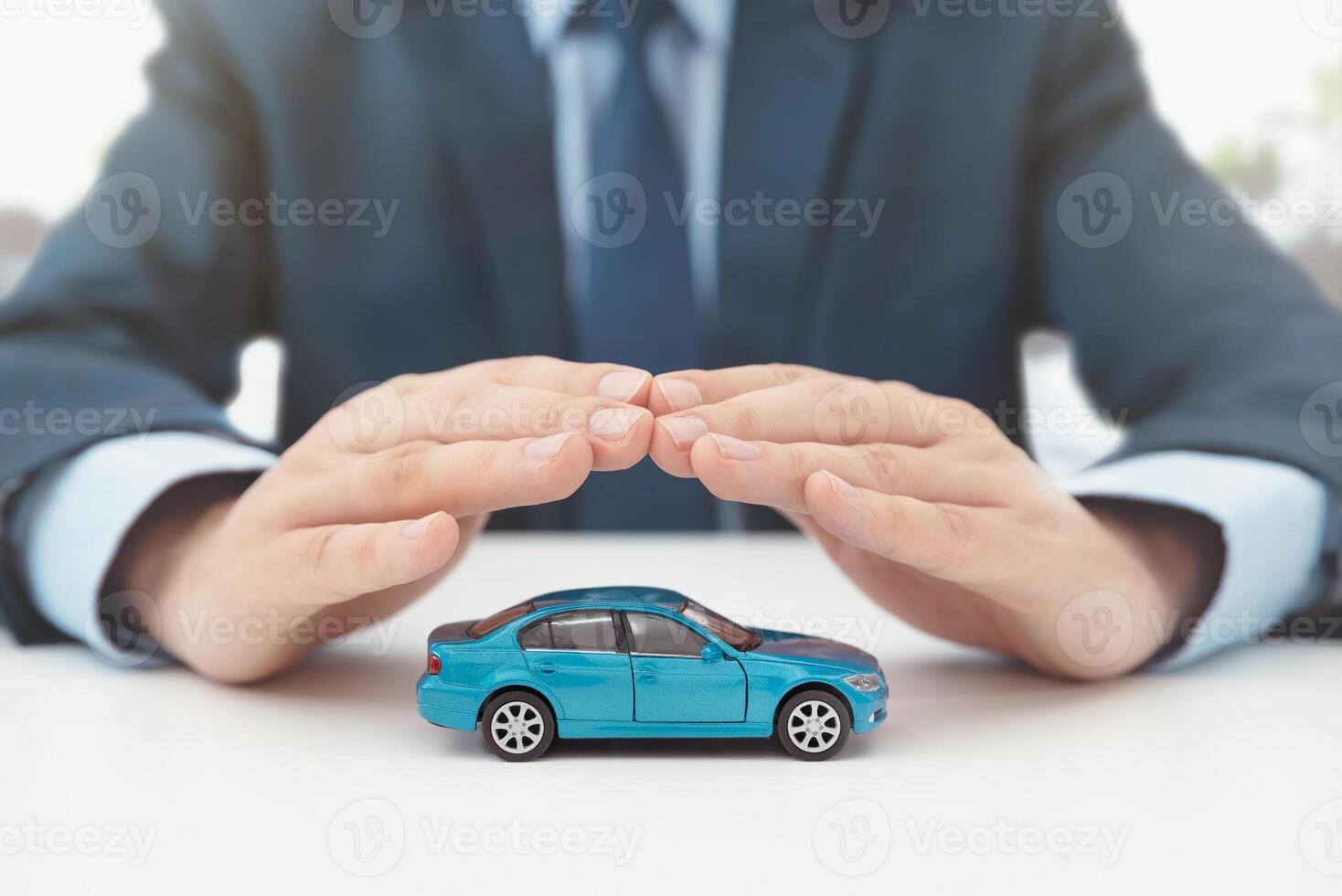 A man in a suit is holding a small car in his hands photo
