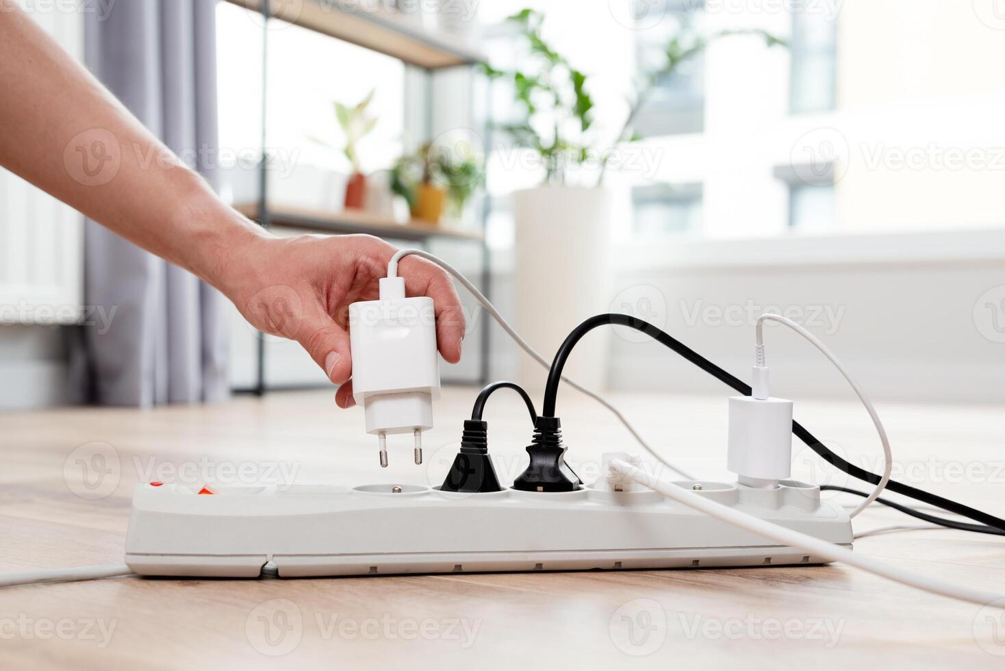 A person is holding an electrical outlet and plugging in a cord photo