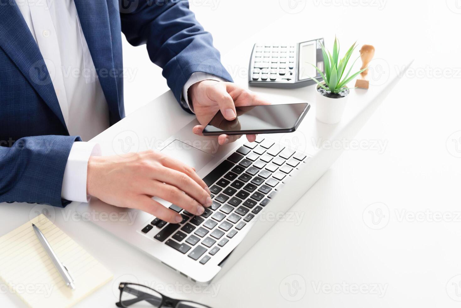 Businessman using smartphone and laptop at desk photo
