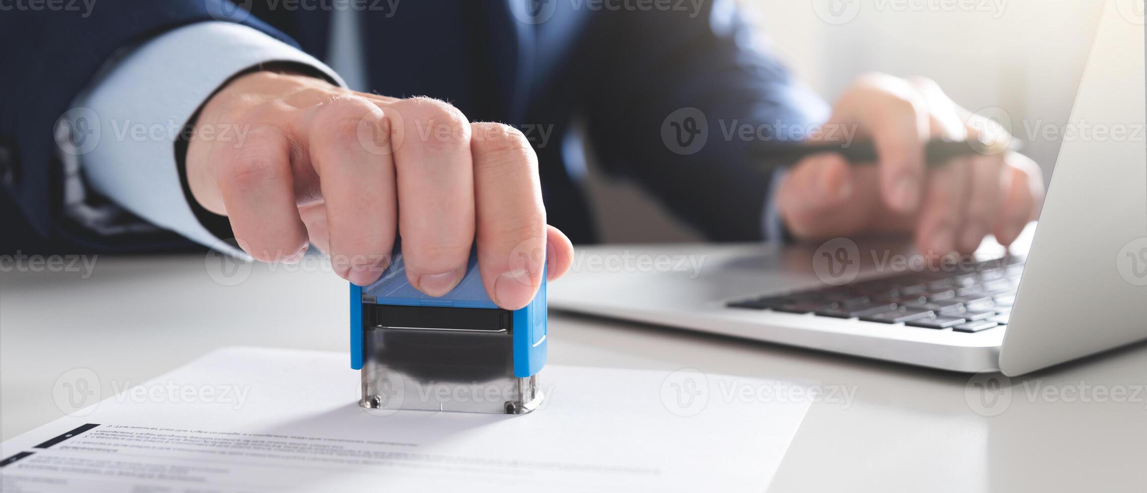 A person in a suit is using a stamp to sign a document photo