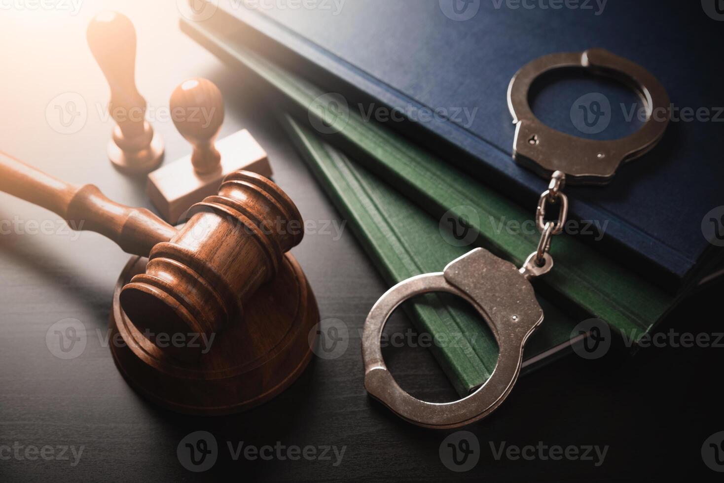 Handcuffs, gavel and books on a wooden table photo