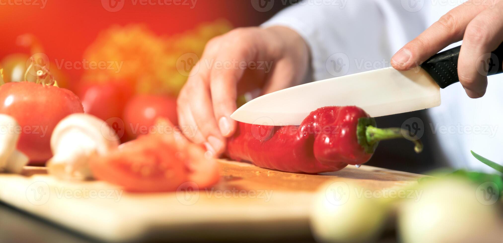 A chef cutting up a red pepper on a cutting board photo