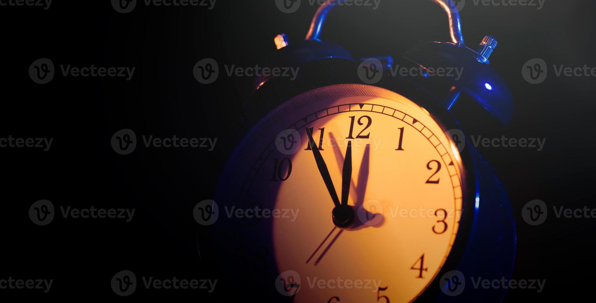 A clock is shown in the dark photo