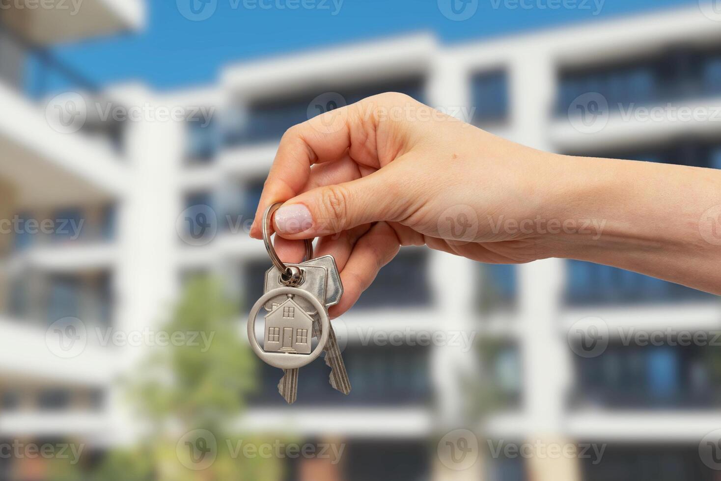 A person holding keys to a house in front of a building photo