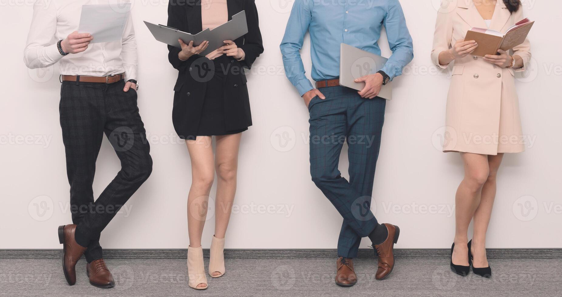 Four business people standing in front of a white wall photo