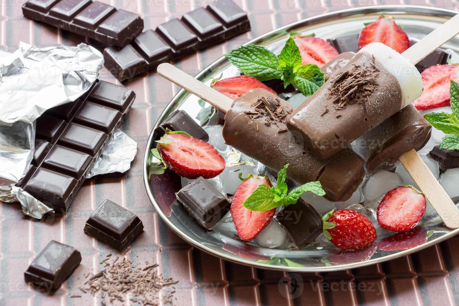 Delicious chocolate ice cream sits on a sleek steel plate, beautifully garnished with fresh strawberries and mint leaves. photo