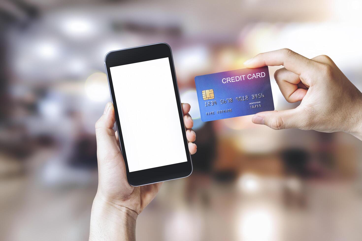 Hands holding credit card with Smart mobile phone show white background for product mockup over for online shopping on shopping mall background, E-payment technology, Concept of internet banking photo